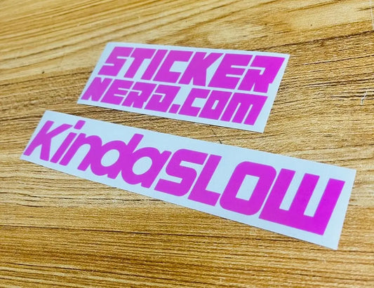 Two die-cut vinyl stickers on a light wood surface. The top sticker reads 'STICKER NERD. Bottom reads 'Kinda Slow'