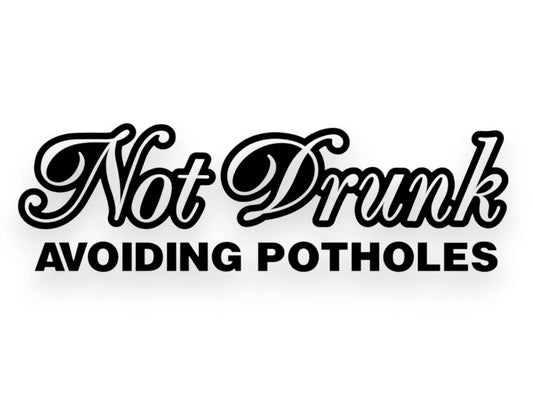 Black vinyl decal with the phrase 'Not Drunk AVOIDING POTHOLE'S' in stylized lettering, shown on a plain white background.