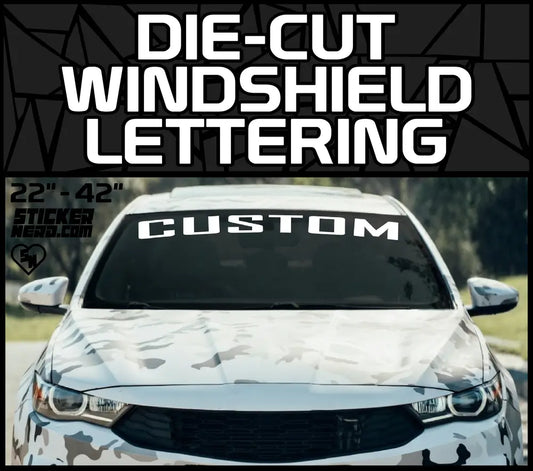 Die-Cut Windshield Lettering banner featuring a custom white text decal on a camouflage wrapped car windshield